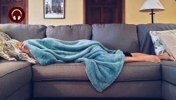 How long am I contagious? A person is lying on their couch with their head under a blanket