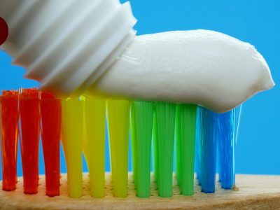 How do I choose the right toothbrush? An image of a rainbow colored toothbrush with toothpaste on top