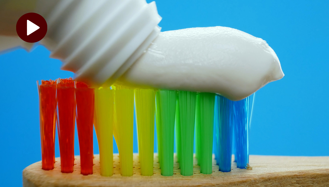 How do I choose the right toothbrush? An image of a rainbow colored toothbrush with toothpaste on top