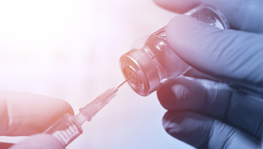 Closeup of vaccine bottle with syringe and needle for immunizati