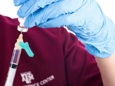 health care professional wearing gloves doses a vaccination into syringe