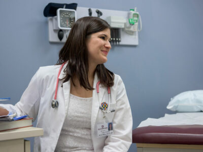Graduate nursing student sits in a clinic exam room