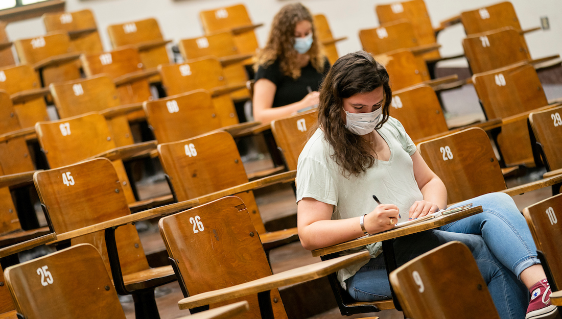 Students wearing masks sit in a lecture hall