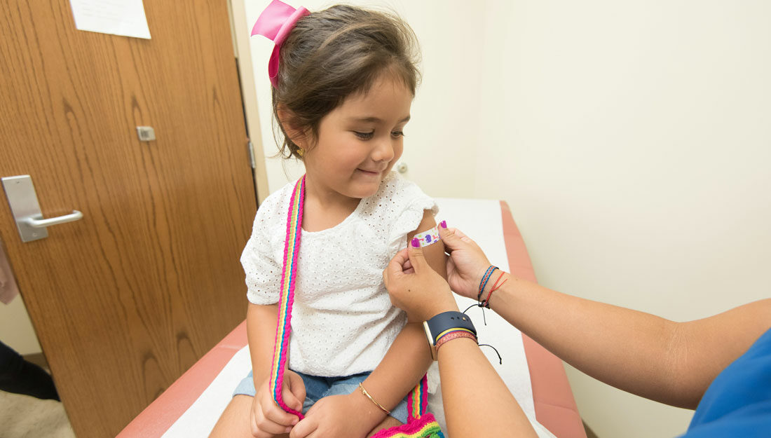 young child receives a bandaid on her arm after being vaccinated