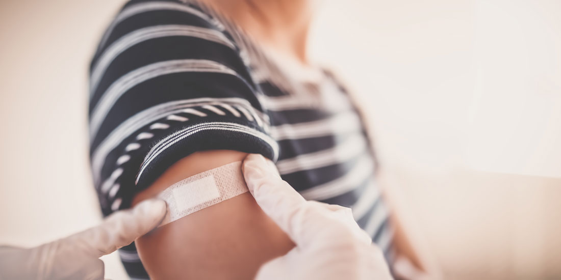 health care professional places bandage on woman's arm after flu shot