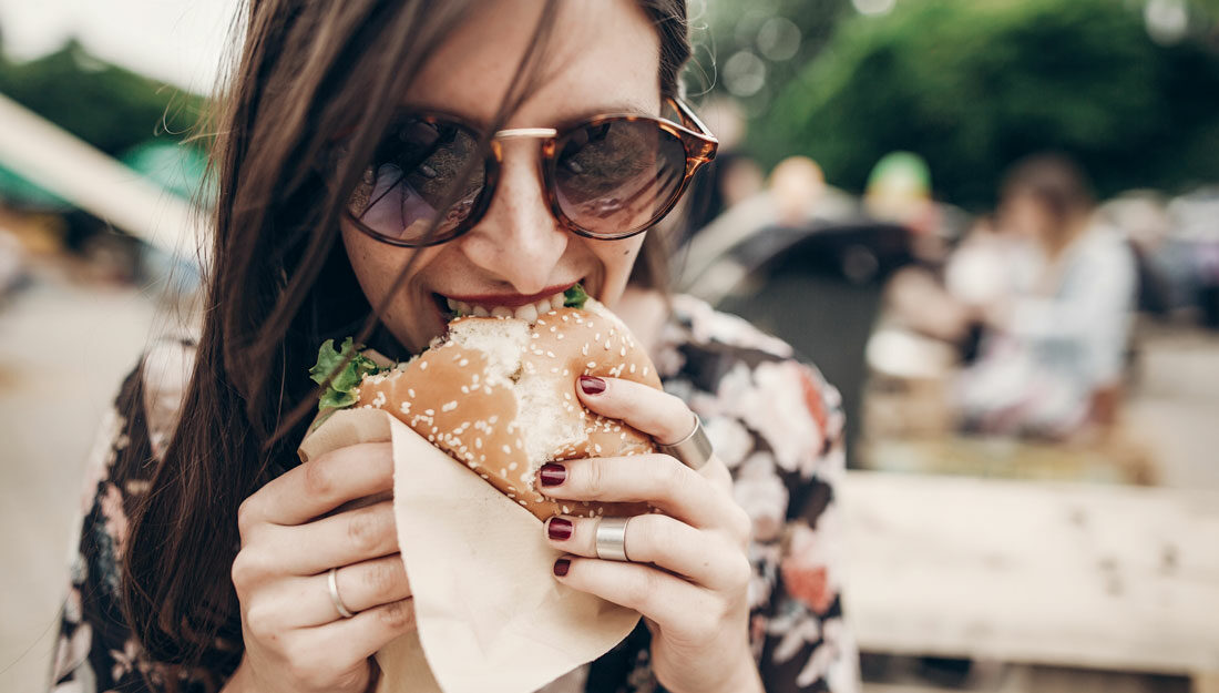 woman holding burger and eating