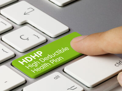 HDHP high deductible health plan Written on Green Key of Metallic Keyboard. Finger pressing key.