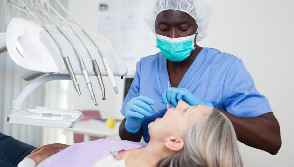 Mature female patient sitting in dental chair. Dental hygienist is treating female patient